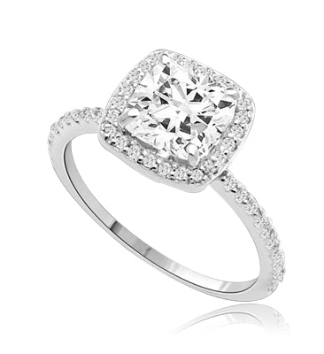 Beautiful Cushion Centerpiece, 1.5 cts, is surrounded by Round Brilliant Melee in this elegant engagement ring. The band consists of round pointer melee to form a brilliant radiance. Appx. 2.5 Ct. T.W. In Platinum Plated Sterling Silver.