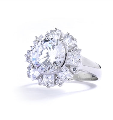 Diamond Essence Designer Ring With Round Brilliant Diamond Essence in center surrounded by alternately set Princess and melee. 7.25 Cts. T.W. set in Platinum Plated Sterling Silver.
