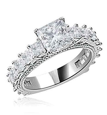 Diamond Essence Designer Ring With 1.50 Cts. of Princess in Center, Accompanied by Small Princess Stones Melee on band, 3 Cts.T.W. In Platinum Plated Sterling Silver.