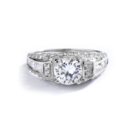 Engagement Ring- 1.0 Ct. round Brilliant Diamond Essence in center with Chanel set Baguettes and Melee going half way down the band. 2.0 Cts. T.W. set in Platinum Plated Sterling Silver.