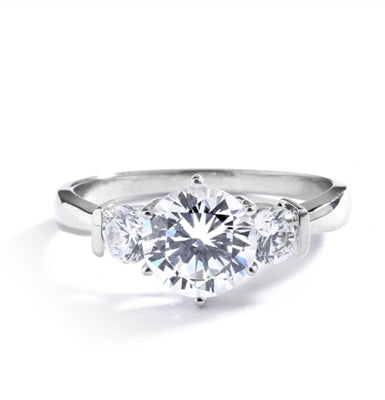 14K Solid White Gold ring features a 2.0 ct. round cut Diamond Essence centerpiece rubbing elbows with two 0.3 round cut masterpices beside it. 2.6 cts. T.W. Breeding shows.