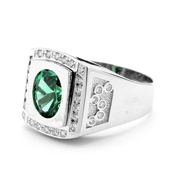 An impressive Men's Ring in two-toned 14K White Gold features a 4.0 cts. Oval Emerald stone set flush in a platform of white gold surrounded by melee, with double jolts of melee on each shank. 4.50 cts. t.w.