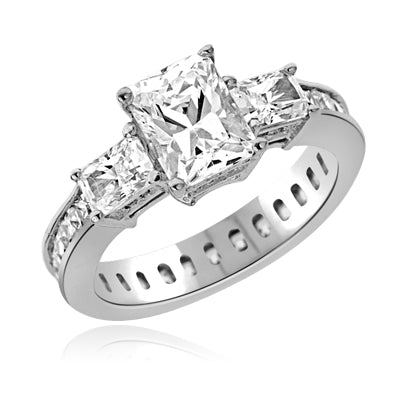 Diamond Essence Ring with Radient Emerald Center Followed by Princess cut Stones And Round Brilliant Melee on the band, 4.50 Cts.T.W. set in Platinum Plated Sterling Silver.